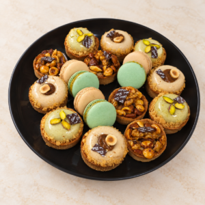 Macarons et tartelettes garnies sur plateau noir pour la pause café Premium Sucrée à Tunis